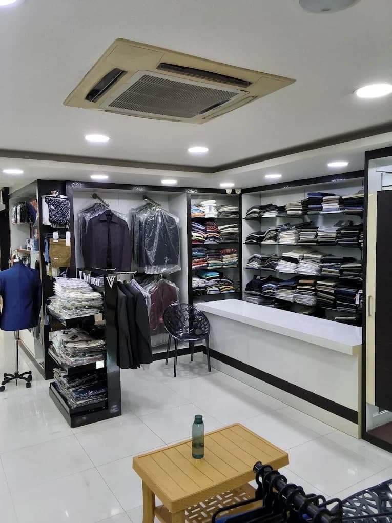 The men's formal section at Laksha Fashion, Hosur, with blazers and suits on hangers and folded shirts on shelves